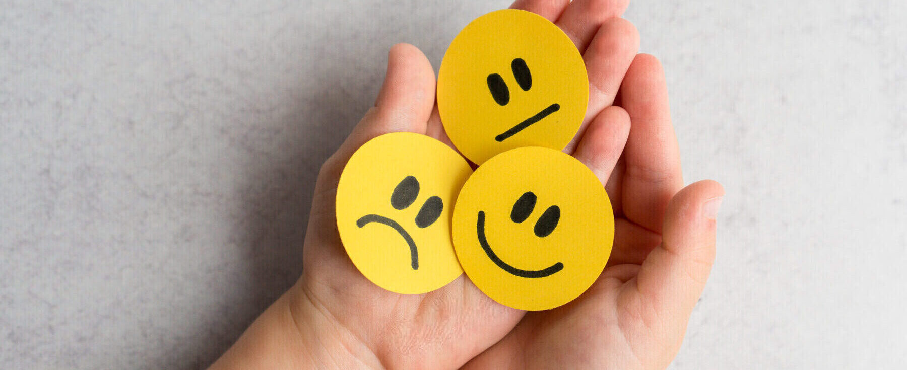 Kid’s hands holding happy, sad and unsatisfied paper faces. 2024/03/iStock-1366828385-e1738781691874.jpg 