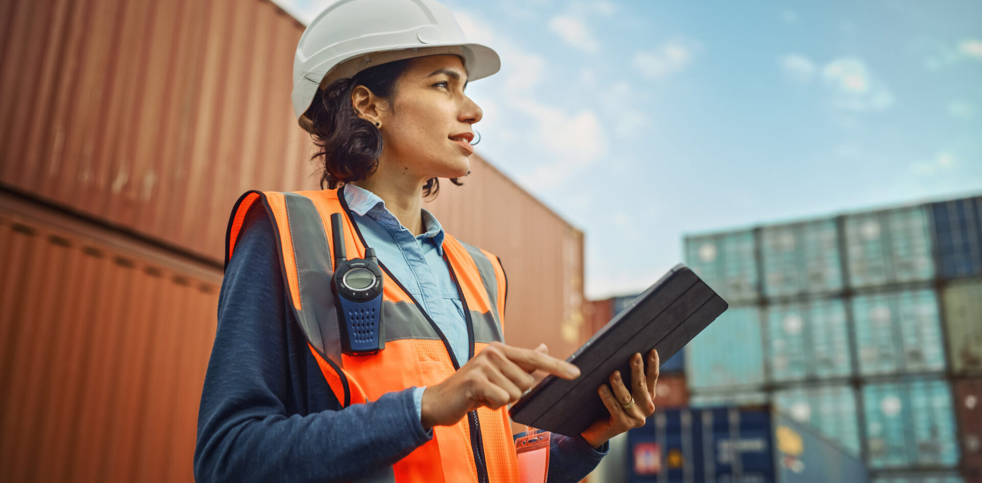 Smiling Portrait of a Beautiful Latin Female Industrial Engineer in White Hard Hat, High-Visibility Vest Working on Tablet Computer. Inspector or Safety Supervisor in Container Terminal. 2025/10/iStock-1309560111-2048x1152-1-e1760920441319.jpeg 